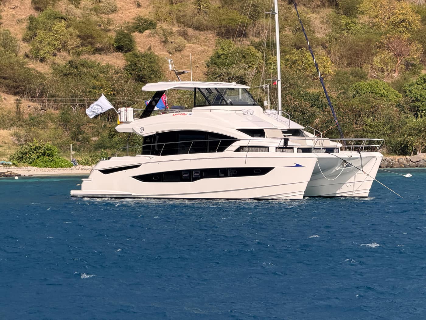 The Wandering Hillbilly, a MarineMax 545 catamaran, at anchor near a hillside.