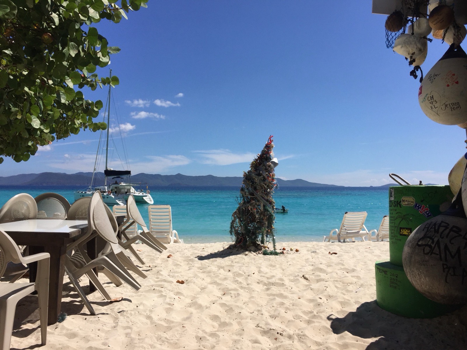 The view over White Bay to St. John from One Love bar, a catamaran anchored in turquoise water.